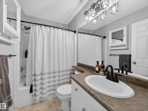 Bathroom with a shower-tub combination, a vanity with a white oval sink, and a large mirror - 1665 Tompkins Place, Edmonton, AB - Indoor Photo Showing Bathroom