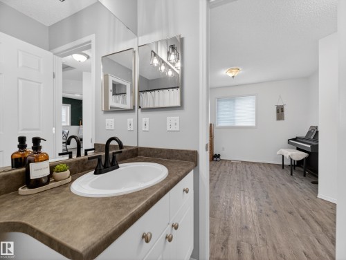 This bathroom features a white vanity with a brown countertop, an oval sink, and a black faucet - 1665 Tompkins Place, Edmonton, AB - Indoor Photo Showing Bathroom