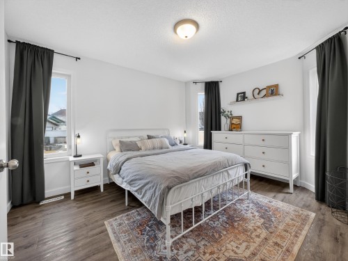This room features light-colored walls, wood-style flooring, and a ceiling light fixture - 1665 Tompkins Place, Edmonton, AB - Indoor Photo Showing Bedroom
