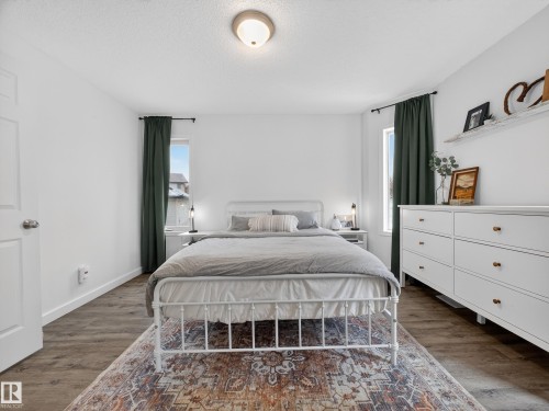 This room features wood-look flooring and white walls, creating a bright and airy feel - 1665 Tompkins Place, Edmonton, AB - Indoor Photo Showing Bedroom