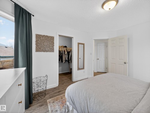 This room features light-colored walls, a window with dark curtains, and wood-style flooring - 1665 Tompkins Place, Edmonton, AB - Indoor Photo Showing Bedroom