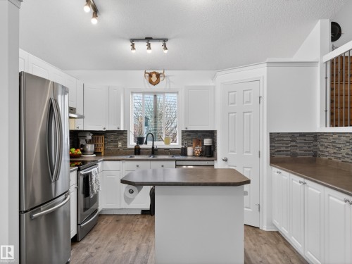 Well-appointed kitchen featuring white cabinetry, stainless steel appliances, a tiled backsplash, and an island with a countertop - 1665 Tompkins Place, Edmonton, AB - Indoor Photo Showing Kitchen With Stainless Steel Kitchen With Double Sink