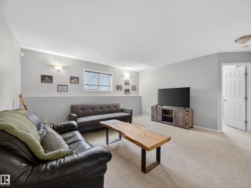 Living room featuring light-colored carpeting, a window with blinds, and white trim - 1665 Tompkins Place, Edmonton, AB - Indoor Photo Showing Living Room