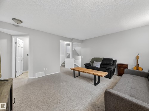 Living area featuring light grey walls, carpeted flooring, and a white door leading to another room - 1665 Tompkins Place, Edmonton, AB - Indoor Photo Showing Living Room