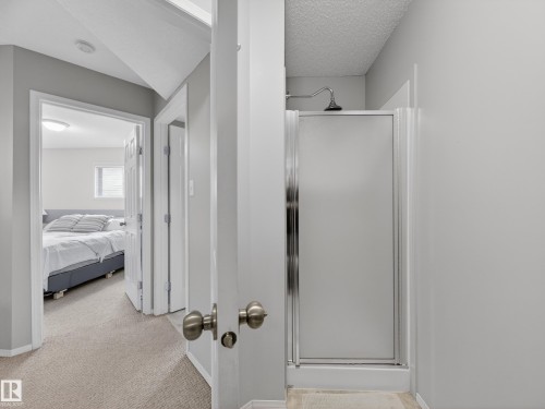 A well-lit interior with neutral colored walls and a shower stall featuring a frosted glass door - 1665 Tompkins Place, Edmonton, AB - Indoor