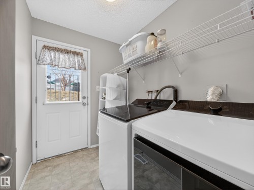 The utility area features a tiled floor, a white exterior door with a window, and a wire storage shelf - 1665 Tompkins Place, Edmonton, AB - Indoor