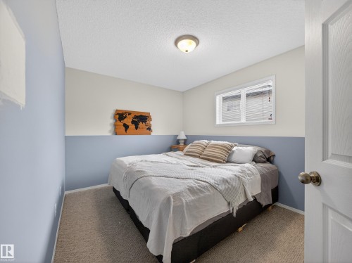 The property features a bedroom with neutral carpet flooring and a window providing natural light - 1665 Tompkins Place, Edmonton, AB - Indoor Photo Showing Bedroom
