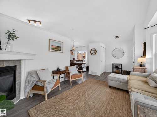 The property features a spacious living area with dark flooring, light-colored walls, and a fireplace with a tiled surround - 1665 Tompkins Place, Edmonton, AB - Indoor Photo Showing Living Room With Fireplace