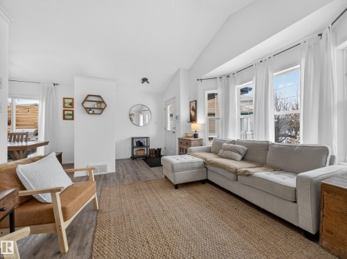 The living area features a large area rug, light-colored flooring, and numerous windows providing natural light - 1665 Tompkins Place, Edmonton, AB - Indoor Photo Showing Living Room