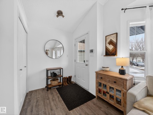 The property features a bright entryway with wood-look flooring, a white front door with a window, and a vaulted ceiling - 1665 Tompkins Place, Edmonton, AB - Indoor Photo Showing Other Room