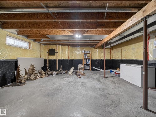 The unfinished basement features exposed wooden beams, a concrete floor, and a window - 1665 Tompkins Place, Edmonton, AB - Indoor Photo Showing Basement
