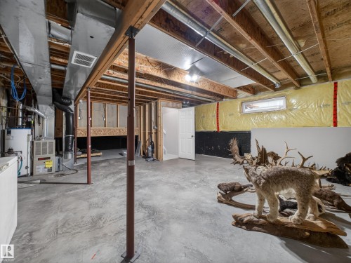 The property features a spacious unfinished basement with a concrete floor, exposed wooden beams, and a window - 1665 Tompkins Place, Edmonton, AB - Indoor Photo Showing Basement
