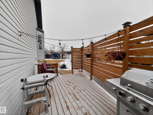 Outdoor deck featuring wooden planks, a privacy fence with a horizontal slat design, and string lights - 1665 Tompkins Place, Edmonton, AB - Outdoor With Exterior