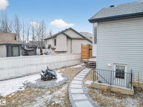 The property features an exterior with light-colored siding, a dark roof, and a wooden deck with stairs - 1665 Tompkins Place, Edmonton, AB - Outdoor With Exterior