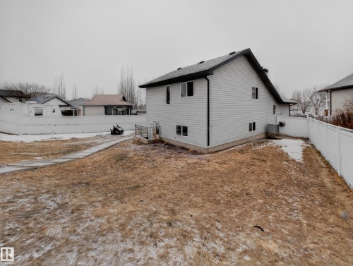 The property includes a fenced yard, a concrete pathway, and a two-story exterior with white siding and a dark roof - 1665 Tompkins Place, Edmonton, AB - Outdoor With Exterior