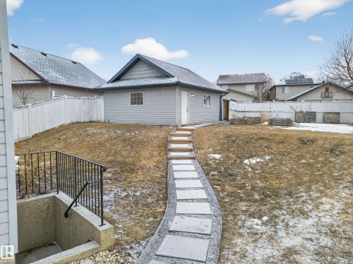The property features an outbuilding with gray siding and a gray roof, accessible via a curved pathway of stepping stones - 1665 Tompkins Place, Edmonton, AB - Outdoor