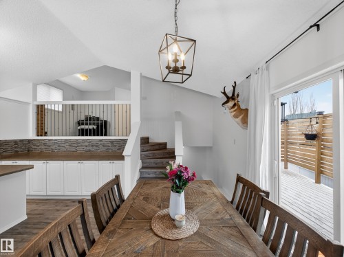 The property features a dining area with a rustic wooden table and chairs, illuminated by a geometric pendant light fixture - 1665 Tompkins Place, Edmonton, AB - Indoor Photo Showing Dining Room