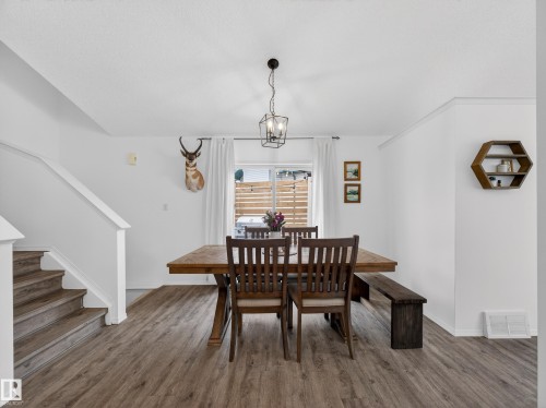 The property features a dining area with wood-look flooring and a contemporary chandelier - 1665 Tompkins Place, Edmonton, AB - Indoor Photo Showing Dining Room