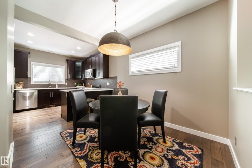 The kitchen features dark wood cabinetry, stainless steel appliances, and a kitchen island with a light-colored countertop - 3451 Cutler Crescent, Edmonton, AB - Indoor Photo Showing Dining Room