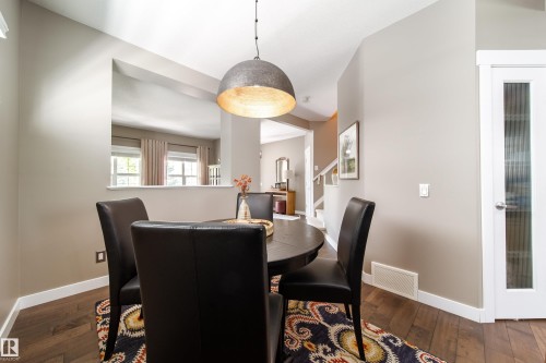 Dining area featuring hardwood floors, a modern pendant light fixture, and a white interior door with frosted glass - 3451 Cutler Crescent, Edmonton, AB - Indoor Photo Showing Dining Room