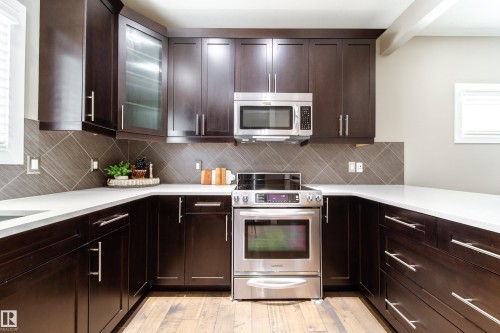 Kitchen featuring dark wood cabinetry, light-colored countertops, and a tiled backsplash - 3451 Cutler Crescent, Edmonton, AB - Indoor Photo Showing Kitchen
