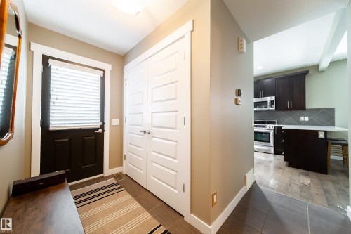 Inviting entryway featuring a dark-paneled door, white bi-fold closet doors, and hardwood flooring - 3451 Cutler Crescent, Edmonton, AB - Indoor Photo Showing Other Room