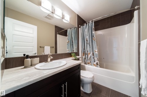 Bathroom featuring a dark wood vanity with a light-colored countertop, a white oval sink, and a large mirror - 3451 Cutler Crescent, Edmonton, AB - Indoor Photo Showing Bathroom