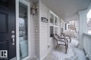 The property features a welcoming front porch with white railings and two chairs, alongside a dark-colored entry door with a decorative glass insert - 3451 Cutler Crescent, Edmonton, AB  - Outdoor With Exterior 