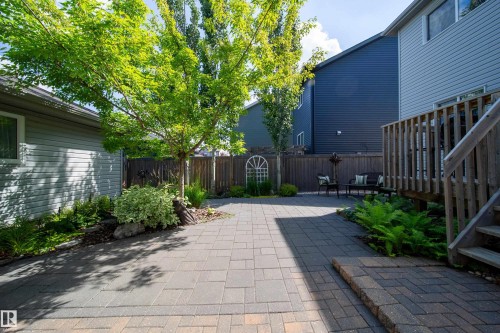The property features a paved patio area, a wooden fence, and mature trees, offering a private outdoor space - 3451 Cutler Crescent, Edmonton, AB - Outdoor