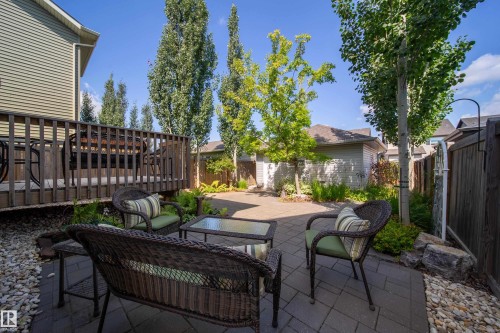 The property features a spacious backyard with a paved patio area, a wooden deck, and mature trees providing natural shade - 3451 Cutler Crescent, Edmonton, AB - Outdoor With Deck Patio Veranda