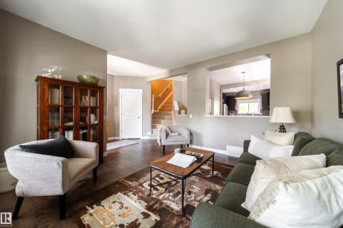 The living area features wood flooring, a pass-through window to the kitchen, and a staircase leading to an upper level - 3451 Cutler Crescent, Edmonton, AB - Indoor Photo Showing Living Room