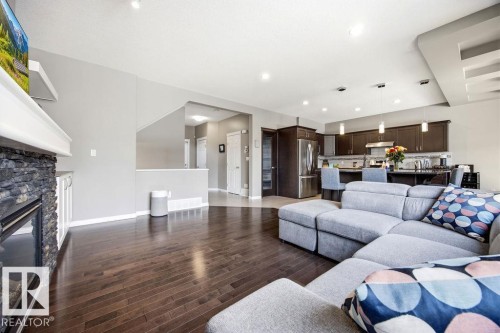 Open concept living area with dark wood flooring, a stone fireplace, and recessed lighting - 13024 206 Street, Edmonton, AB - Indoor Photo Showing Living Room With Fireplace