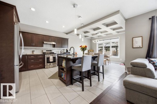 The kitchen features dark wood cabinetry, stainless steel appliances, and an island with seating - 13024 206 Street, Edmonton, AB - Indoor Photo Showing Other Room