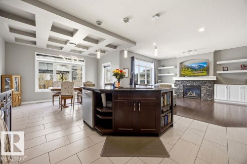 The property offers an open-concept living space with a kitchen island featuring dark wood cabinetry, a granite countertop, and a built-in bookshelf - 13024 206 Street, Edmonton, AB - Indoor With Fireplace