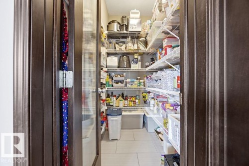 This spacious pantry features wire shelving for organization, a light-colored tile floor, and a dark wood door with a glass insert - 13024 206 Street, Edmonton, AB - Indoor Photo Showing Other Room
