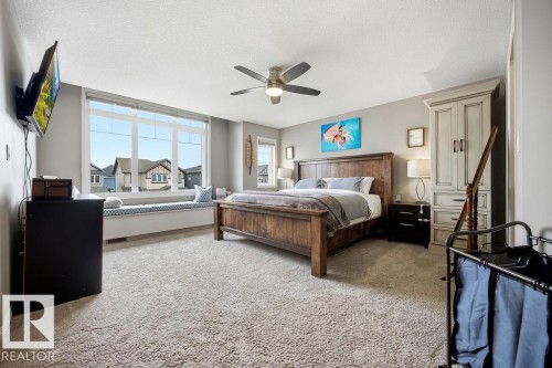 This spacious room features a large window with a built-in window seat, a ceiling fan, and light-colored carpet - 13024 206 Street, Edmonton, AB - Indoor Photo Showing Bedroom