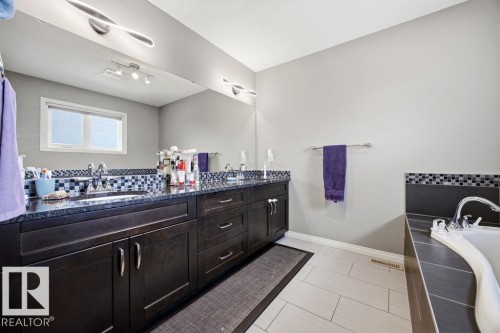 The bathroom features a double vanity with dark wood cabinetry and a dark granite countertop - 13024 206 Street, Edmonton, AB - Indoor Photo Showing Bathroom