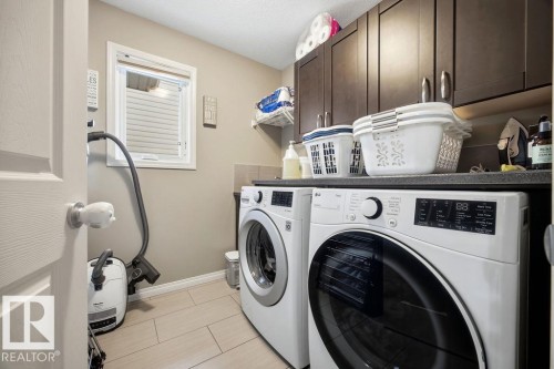 This laundry room features tile flooring, a window providing natural light, and dark wood cabinetry offering storage - 13024 206 Street, Edmonton, AB - Indoor Photo Showing Laundry Room