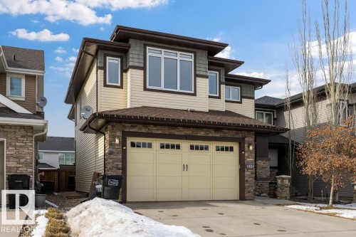 The property features a two-car garage with overhead lighting, a paved driveway, and stone accents - 13024 206 Street, Edmonton, AB - Outdoor