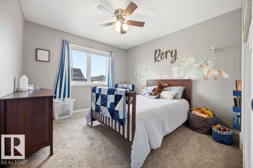 The room features light gray walls, a window with blue and white striped curtains, and a ceiling fan with a light fixture - 13024 206 Street, Edmonton, AB - Indoor Photo Showing Bedroom