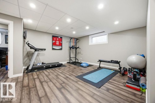 This versatile room features durable wood-look flooring, recessed lighting, and a white drop ceiling - 13024 206 Street, Edmonton, AB - Indoor Photo Showing Gym Room