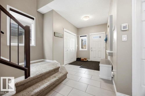 Inviting entryway featuring tile flooring, a carpeted staircase with dark wood railings, and a white front door with window panels - 13024 206 Street, Edmonton, AB - Indoor Photo Showing Other Room