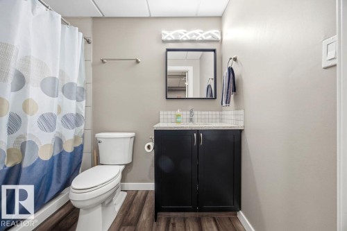 The bathroom features a vanity with a dark cabinet and a countertop, a toilet, and wood-style flooring - 13024 206 Street, Edmonton, AB - Indoor Photo Showing Bathroom