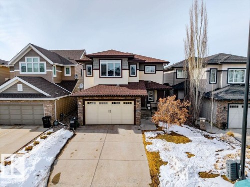 The property features a two-car garage with a paved driveway, and a stone and siding exterior - 13024 206 Street, Edmonton, AB - Outdoor With Facade