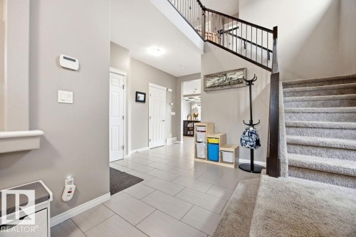 Inviting entryway featuring tile flooring, a carpeted staircase with dark wood banister and wrought iron spindles, and light-colored walls - 13024 206 Street, Edmonton, AB - Indoor Photo Showing Other Room