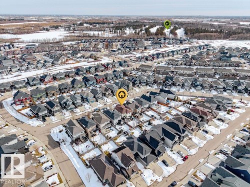 Aerial view of a residential area featuring numerous properties with dark roofs, surrounded by areas of sparse trees and snow-covered ground - 13024 206 Street, Edmonton, AB - Outdoor With View