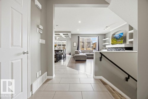 This inviting entryway features light-toned tiled flooring, leading into an open-concept living area with hardwood flooring and large windows - 13024 206 Street, Edmonton, AB - Indoor Photo Showing Other Room
