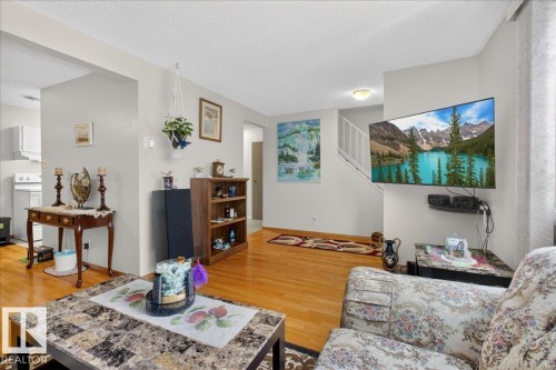 The living area features hardwood flooring, light grey walls, and a staircase with white railings - 2 Mcleod Place, Edmonton, AB - Indoor Photo Showing Living Room
