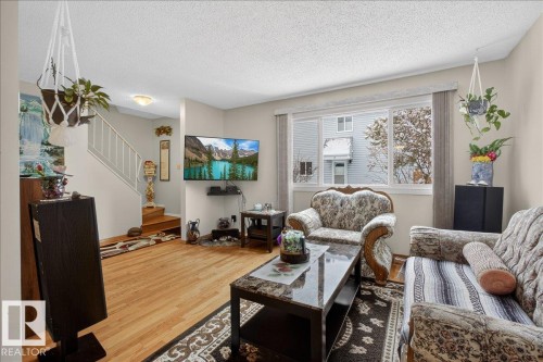 Living area featuring hard surface flooring, a large window, and a staircase with a white railing - 2 Mcleod Place, Edmonton, AB - Indoor Photo Showing Living Room