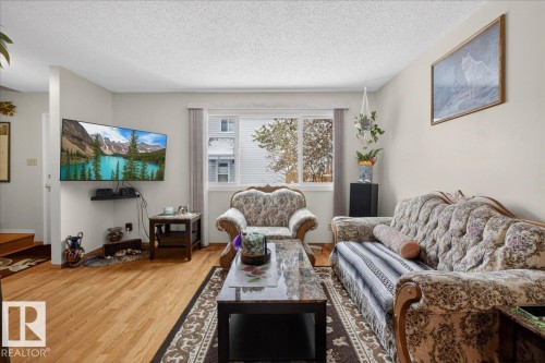 This living space features hardwood flooring, a large window providing natural light, and neutral wall tones - 2 Mcleod Place, Edmonton, AB - Indoor Photo Showing Living Room